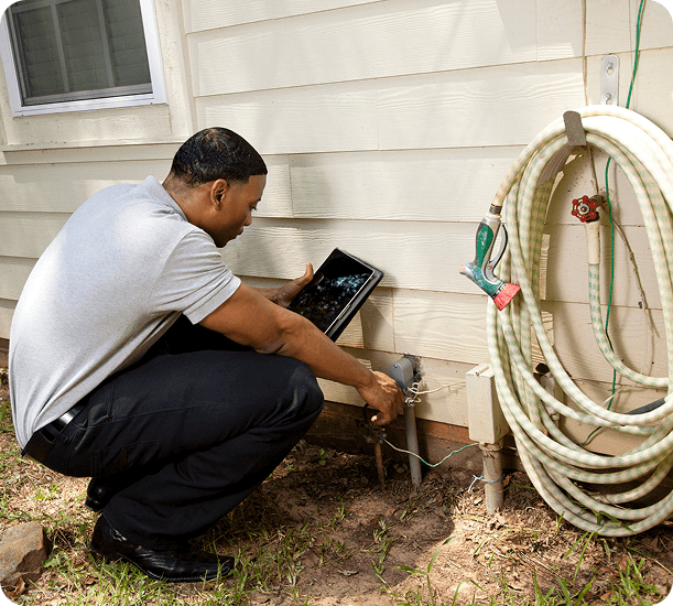 Worker examining exterior water pipes.