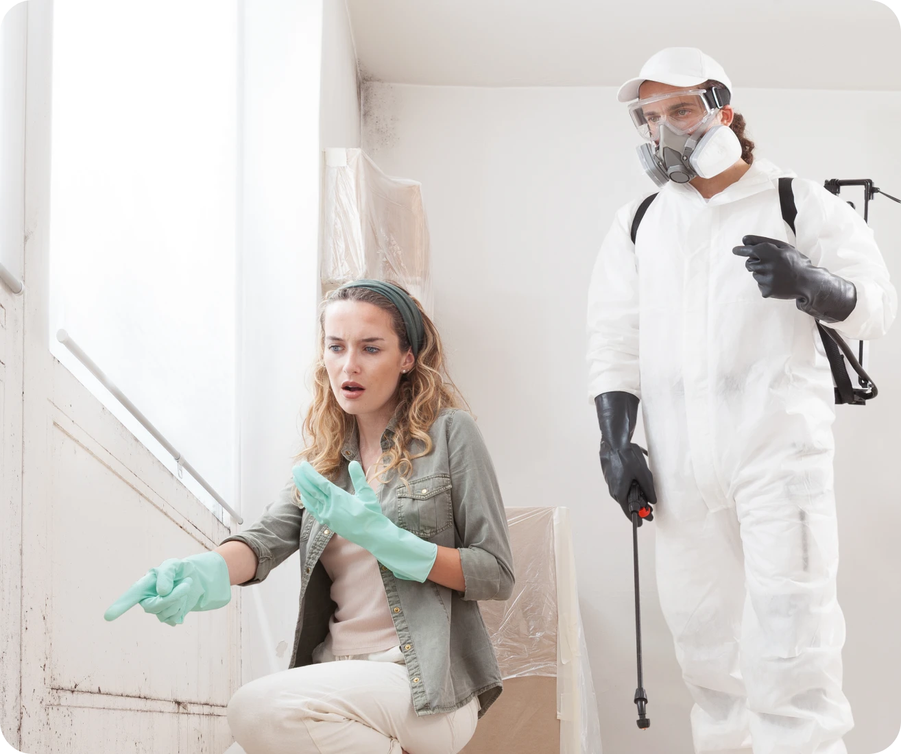Woman and exterminator inspecting moldy wall