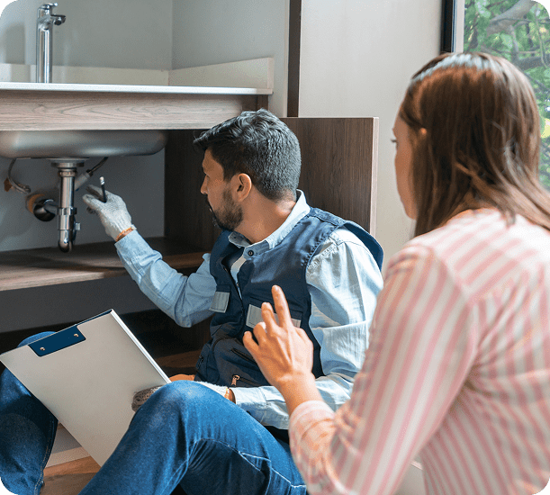 Plumber inspecting under-sink pipes