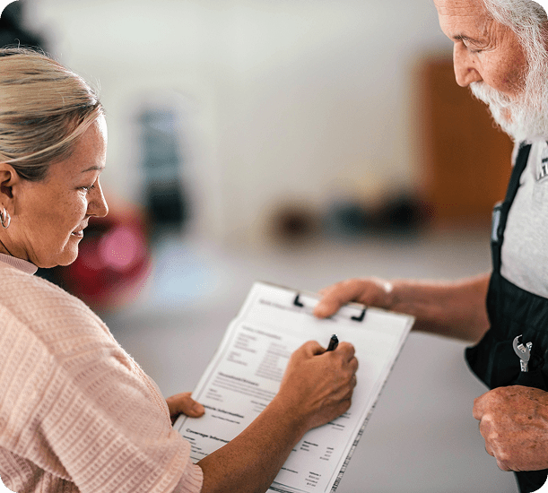 Woman signing a document with man watching.
